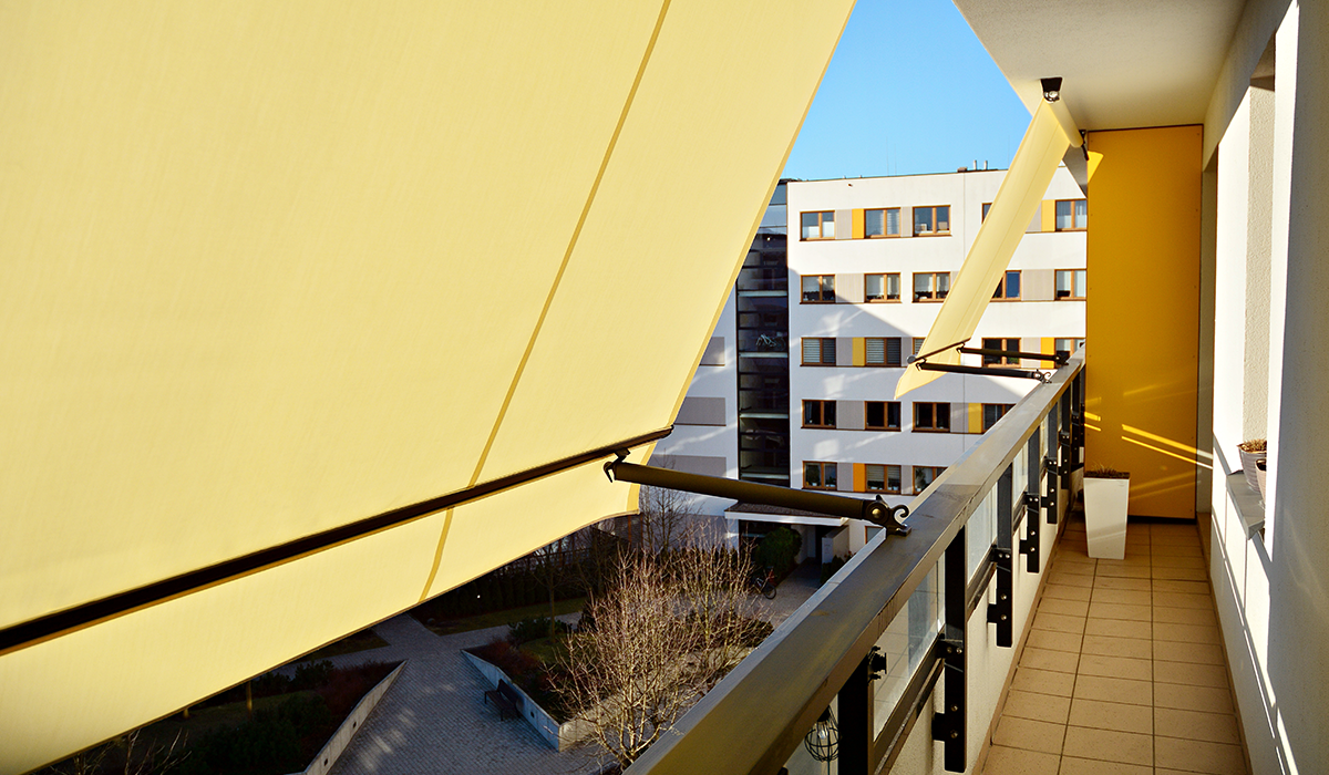 Balcón con toldos amarillos y vista a edificio residencial